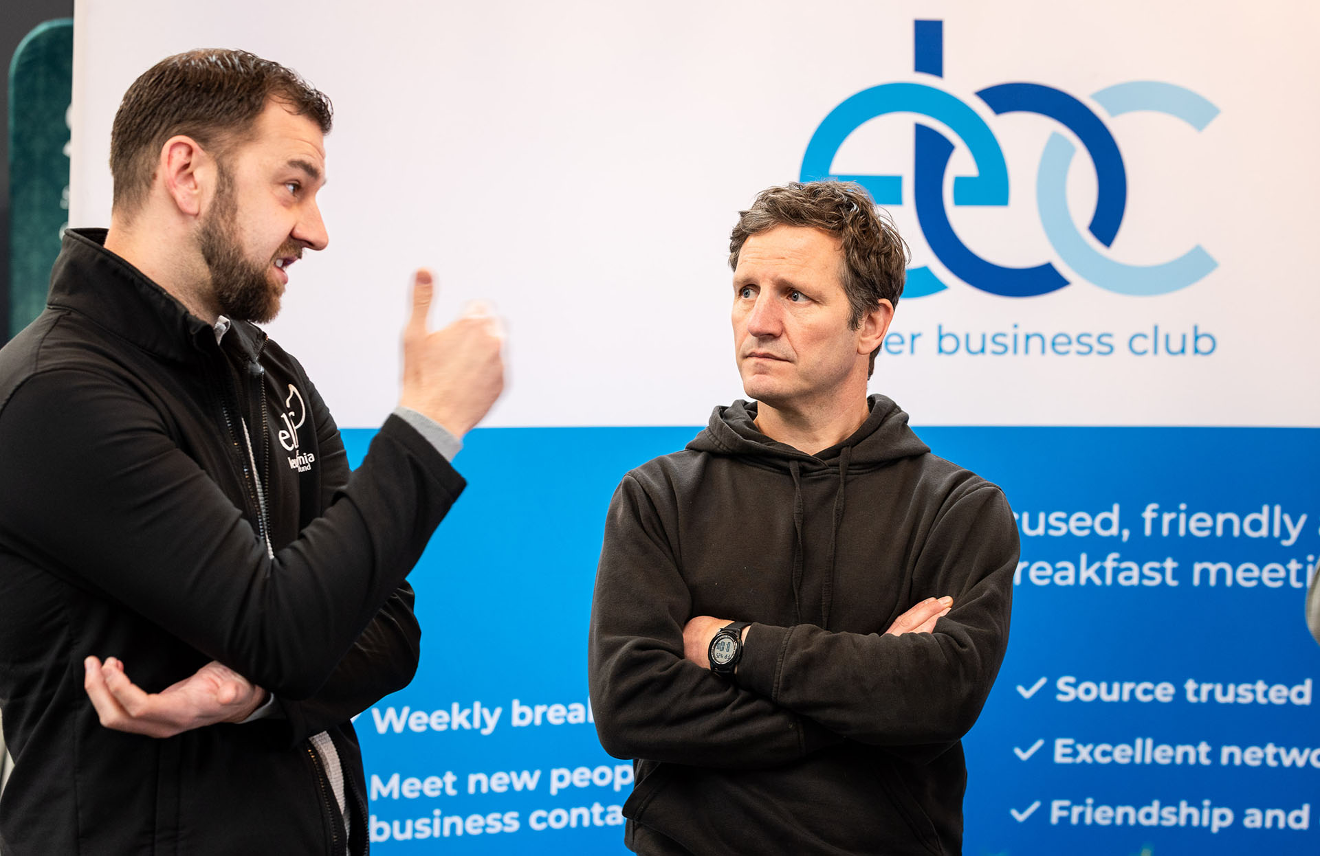Two members chatting in front of the Exeter Business Club banner